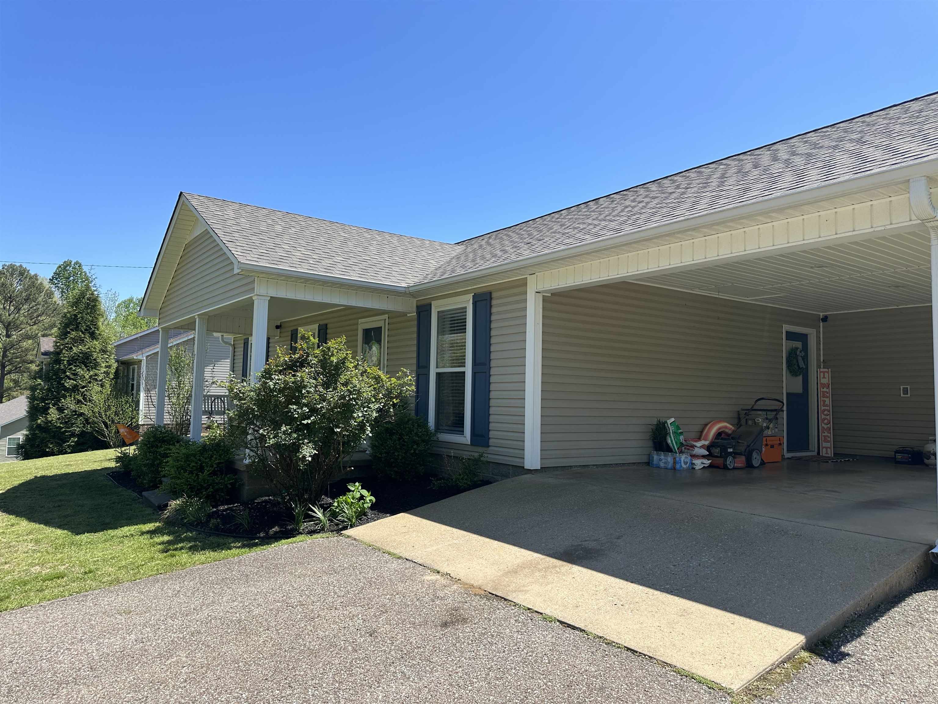 228 Edgewood Drive Adamsville, TN 38310 - Photo 34 of 37 Exterior space with driveway, an attached carport, a lawn, and roof with shingles