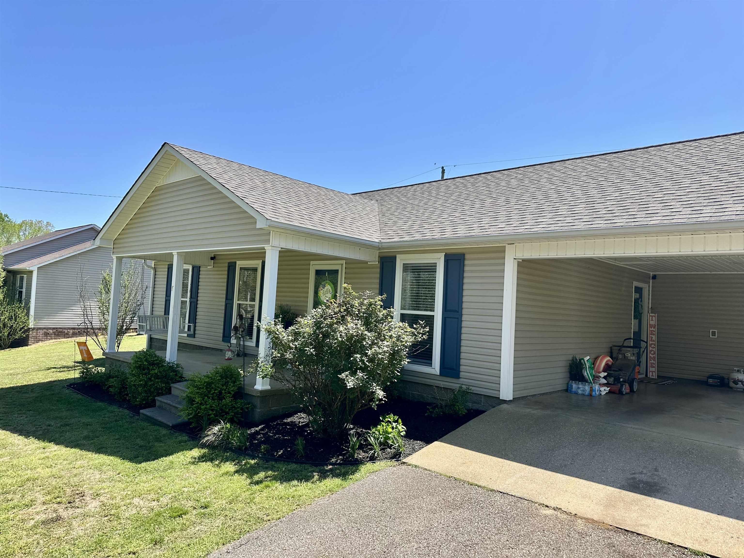 228 Edgewood Drive Adamsville, TN 38310 - Photo 35 of 37 View of front of house featuring a carport, a porch, concrete driveway, a front lawn, and roof with shingles