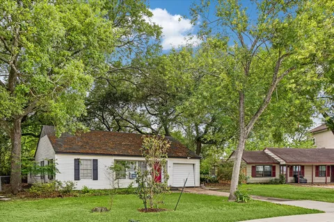 a view of house with a big yard and large trees