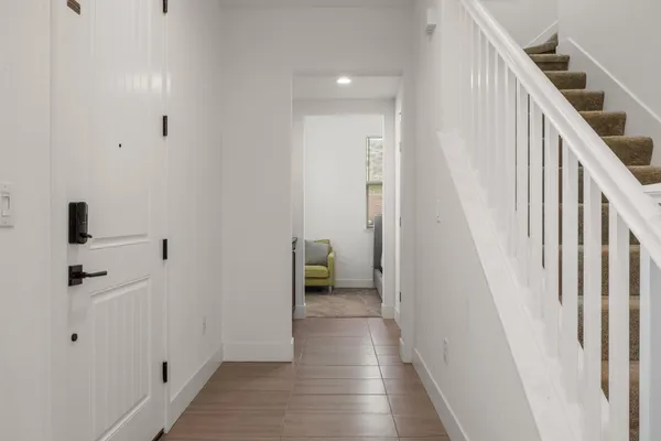 a view of a hallway with white walls and stairs