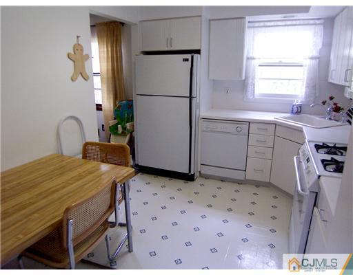 66 East Cliff Road Colonia, NJ 07067 - Photo 7 of 18 a kitchen with a table chairs and a refrigerator