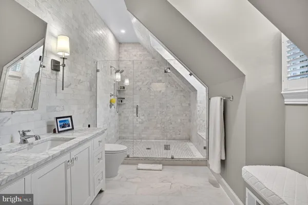 a bathroom with a granite countertop sink a toilet a mirror and shower
