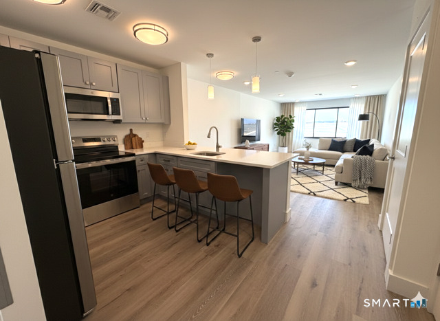 414 Mather Street, Unit 2D Hamden, CT 06514 - Photo 2 of 6 a kitchen with stainless steel appliances kitchen island granite countertop a table chairs stove refrigerator and cabinets