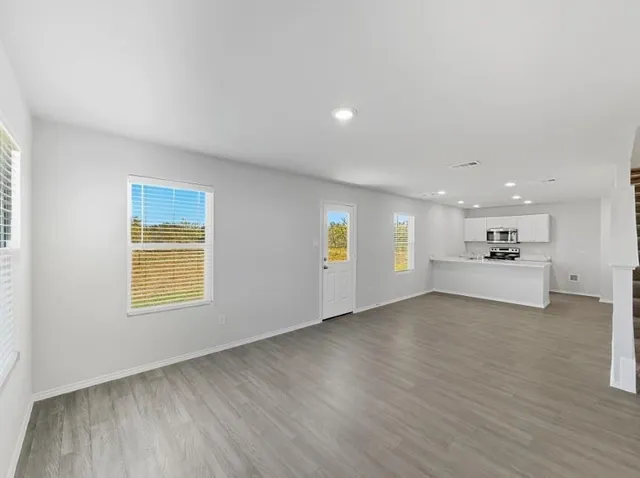 a view of kitchen with stainless steel appliances wooden floor and a large window