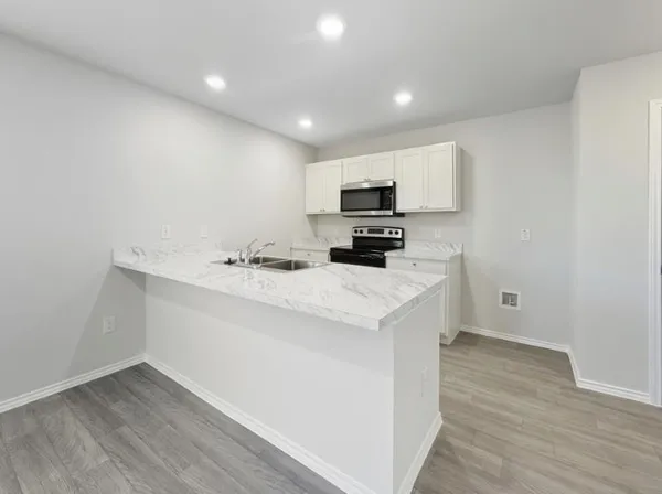 a kitchen with white cabinets and black appliances