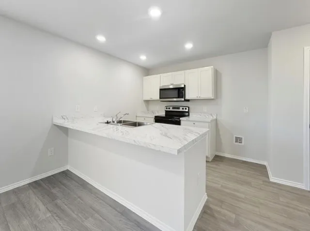 a kitchen with white cabinets and black appliances