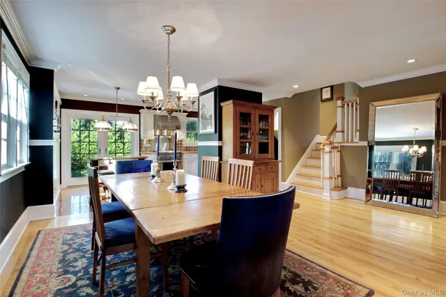 a dining room with wooden floor a chandelier a wooden table and chairs