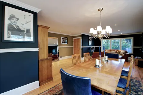 a dining room with wooden floor a chandelier a wooden table and chairs