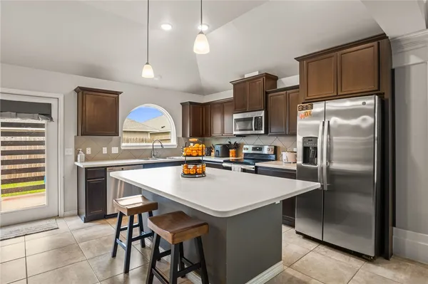 a kitchen with kitchen island a counter space a sink appliances and cabinets