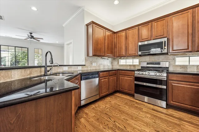 a kitchen with stainless steel appliances granite countertop a sink stove microwave and refrigerator
