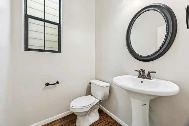 a bathroom with a sink a mirror a toilet and a window