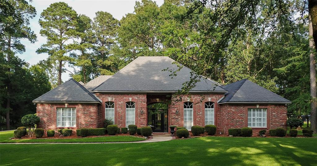 View of front facade featuring brick siding, a front yard, and roof with shingles
