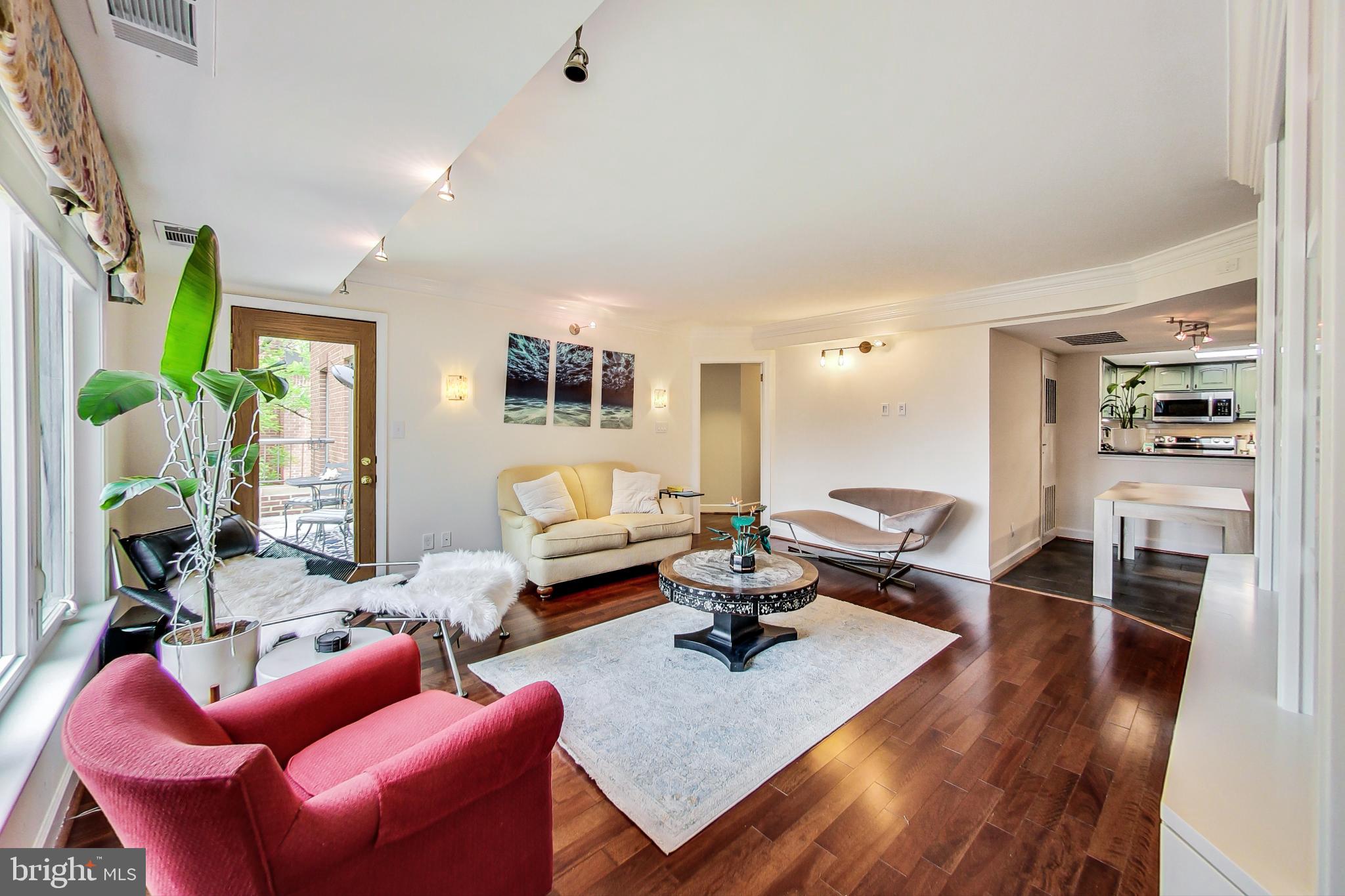 a living room with furniture kitchen view and a wooden floor