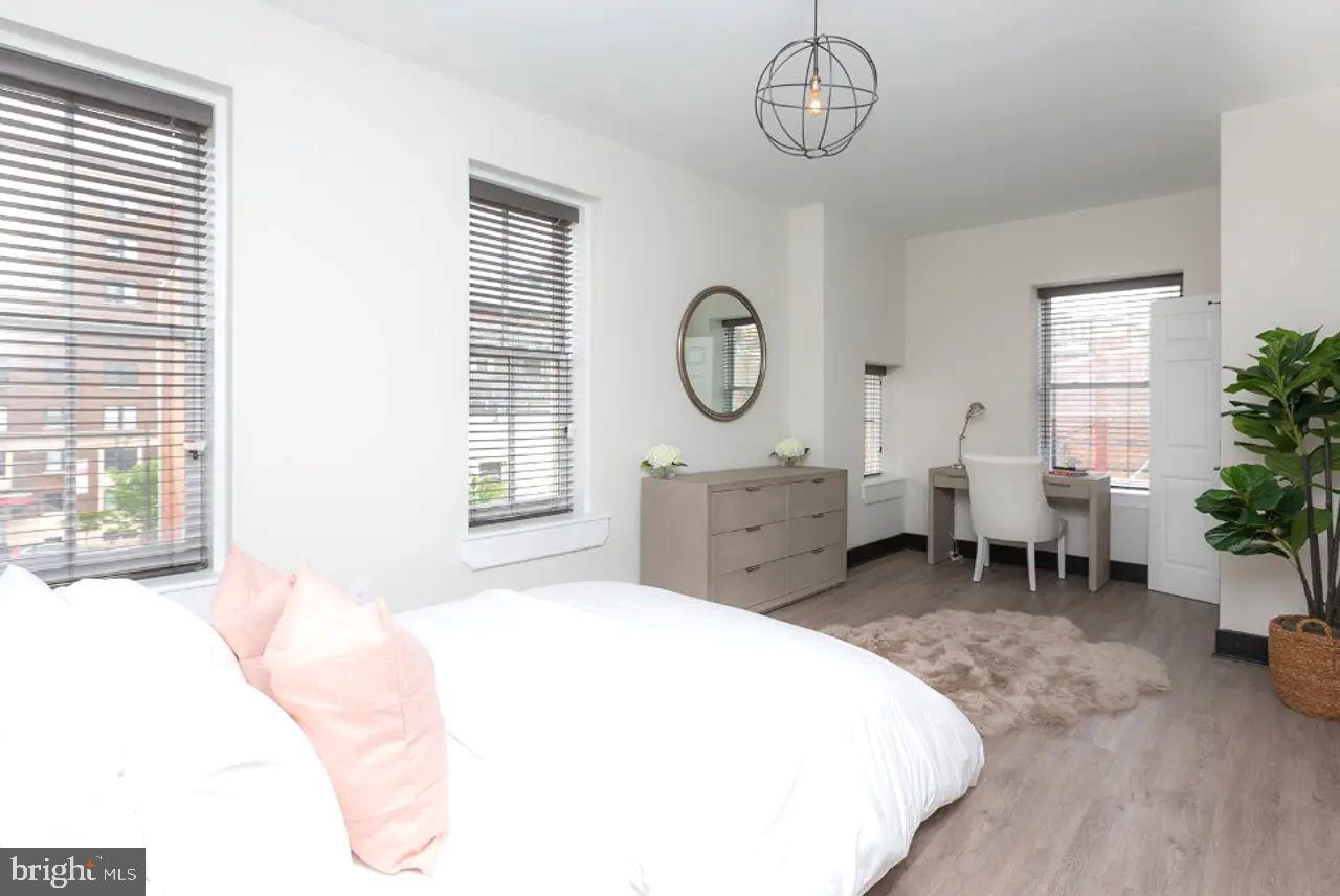 938 North Calvert Street, Unit 1B Baltimore, MD 21202 - Photo 7 of 11 a spacious bedroom with a bed a chandelier a mirror and a window