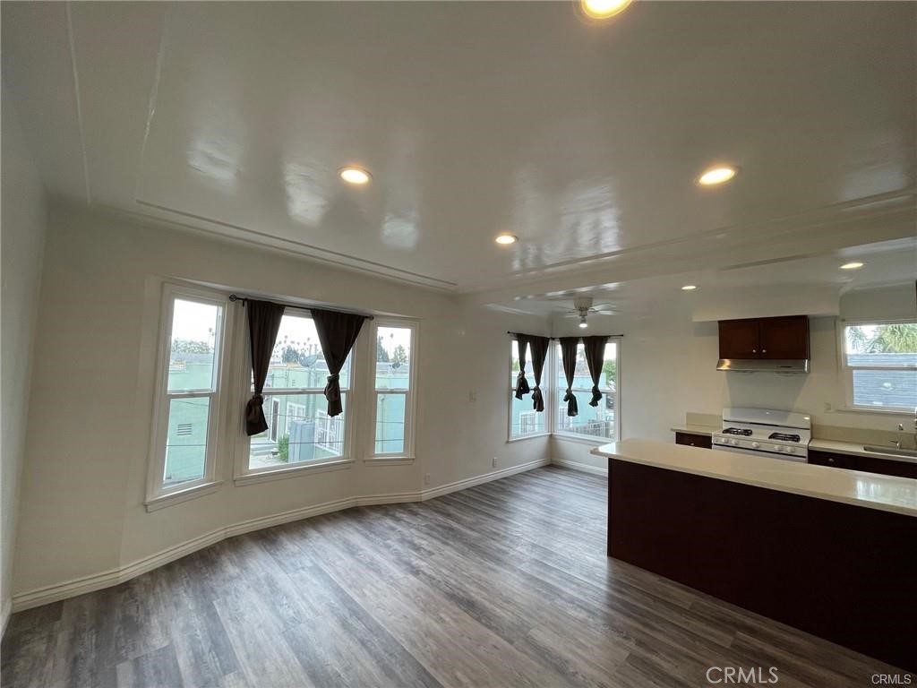 a living room with stainless steel appliances kitchen island hardwood floor and a large window