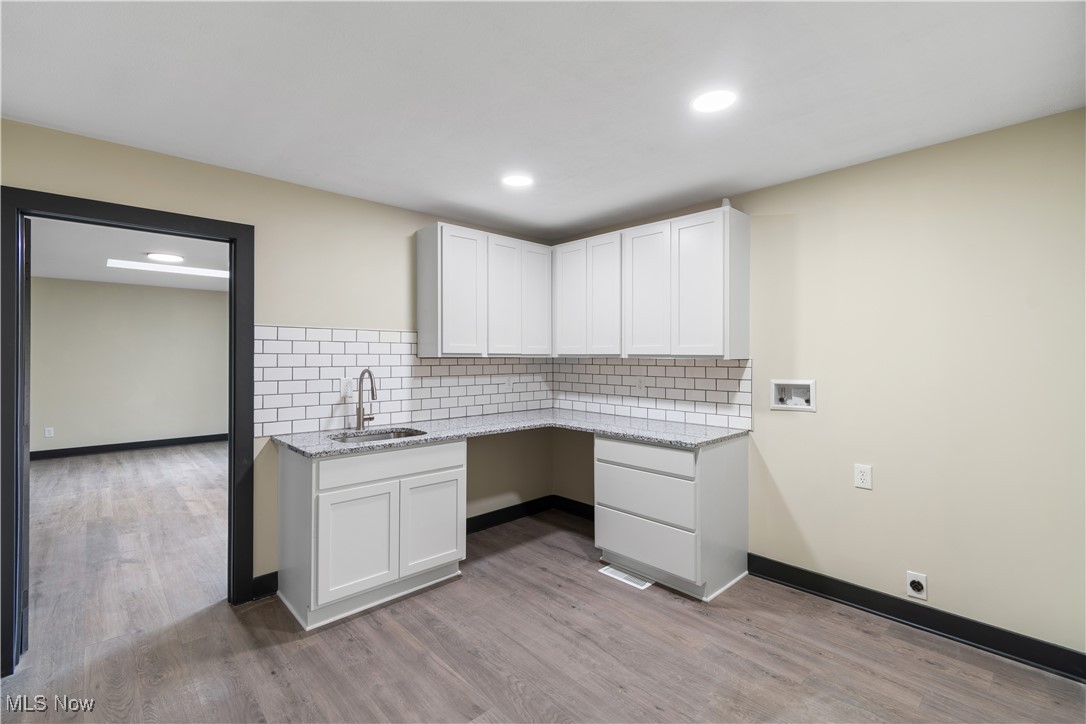 2201 Ridgewood Road Medina, OH 44256 - Photo 24 of 50 Kitchen with tasteful backsplash, light wood-style flooring, white cabinets, light stone countertops, and recessed lighting