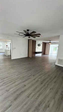 a view of an empty room with a window and wooden floor