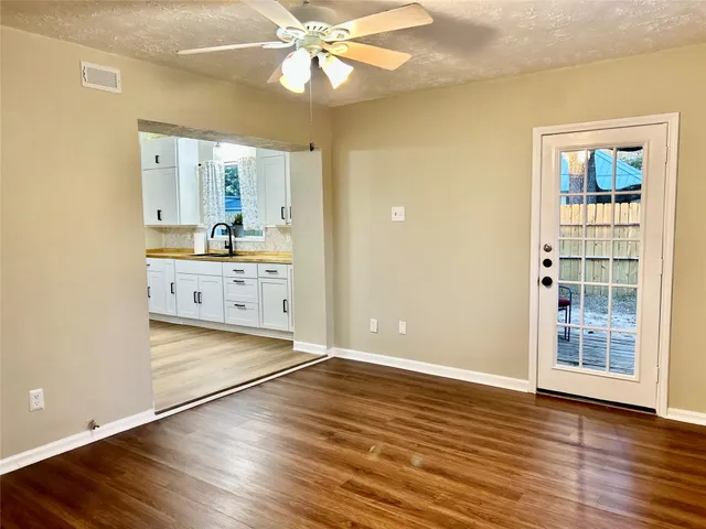 an empty room with wooden floor cabinet and windows