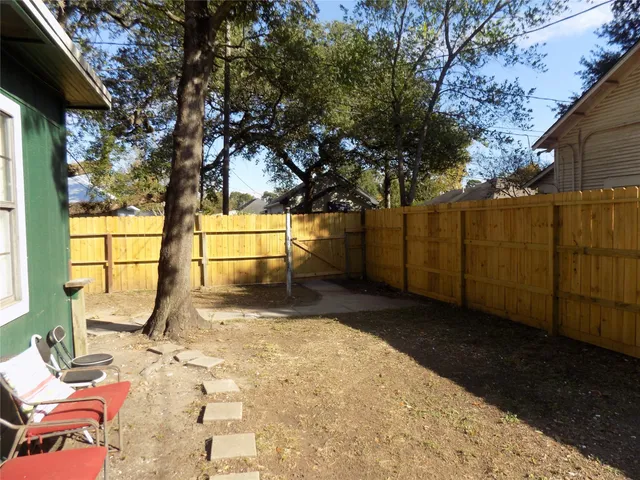 a view of backyard with wooden fence and large trees