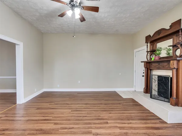 a view of an empty room with wooden floor and a fireplace