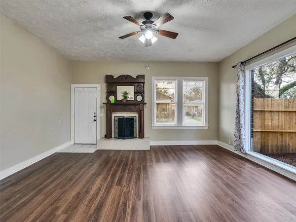 a view of a livingroom with wooden floor a ceiling fan and a window