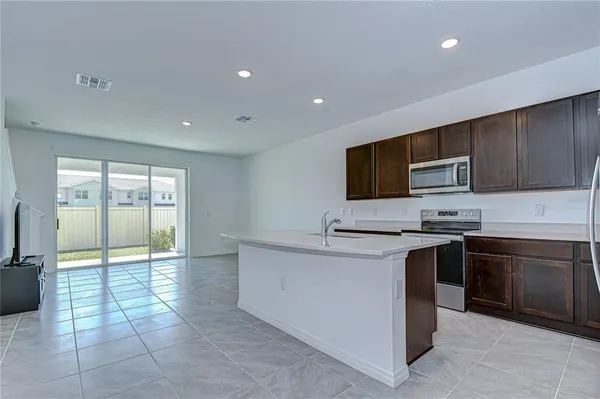 a large kitchen with stainless steel appliances granite countertop a stove a sink and a microwave