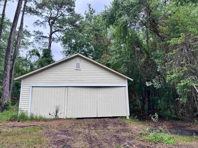 a view of a small house with a yard and large tree