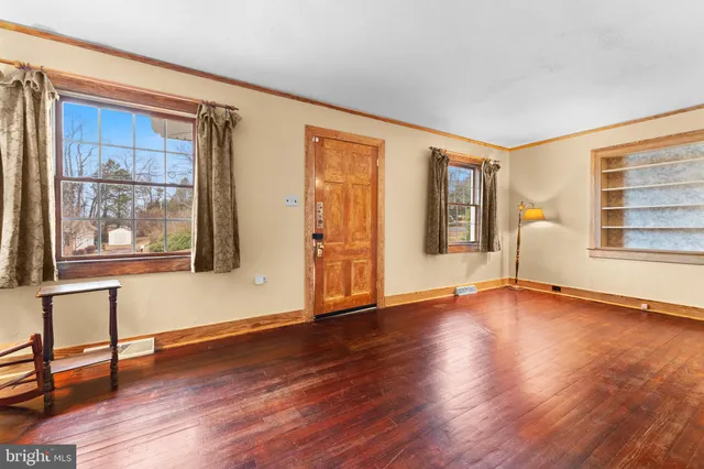 a view of an empty room with window and wooden floor