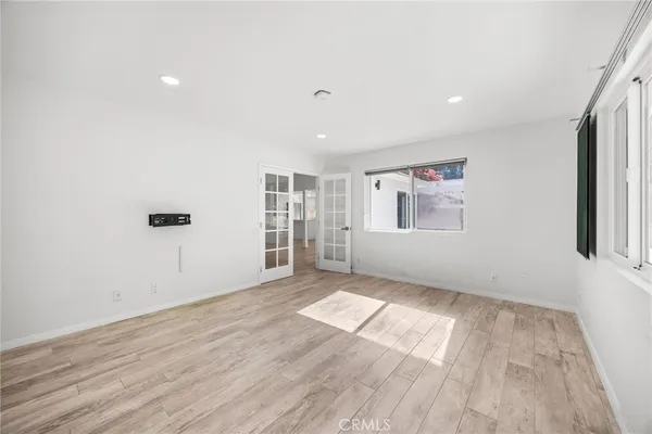 an empty room with wooden floor and windows