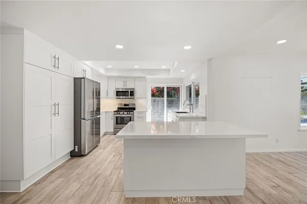 a large kitchen with stainless steel appliances a large counter top a refrigerator and a sink