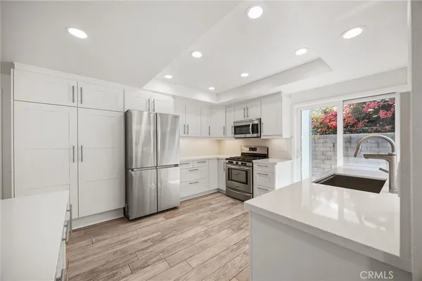 a kitchen with refrigerator a microwave a stove and white cabinets with wooden floor