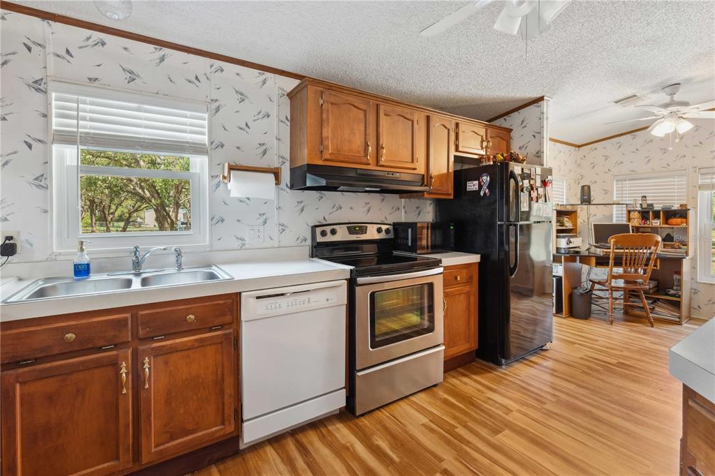 4131 Burwell Road Webster, FL 33597 - Photo 13 of 61 a kitchen with stainless steel appliances granite countertop a refrigerator a sink dishwasher a stove and white countertops with wooden floor