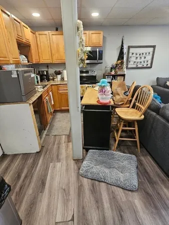 a living room with stainless steel appliances furniture wooden floor and a view of kitchen