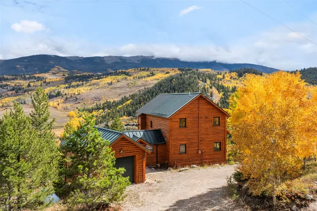 a front view of a house with a yard and mountain view in back