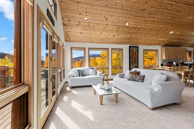 a living room with furniture a flat screen tv and floor to ceiling window