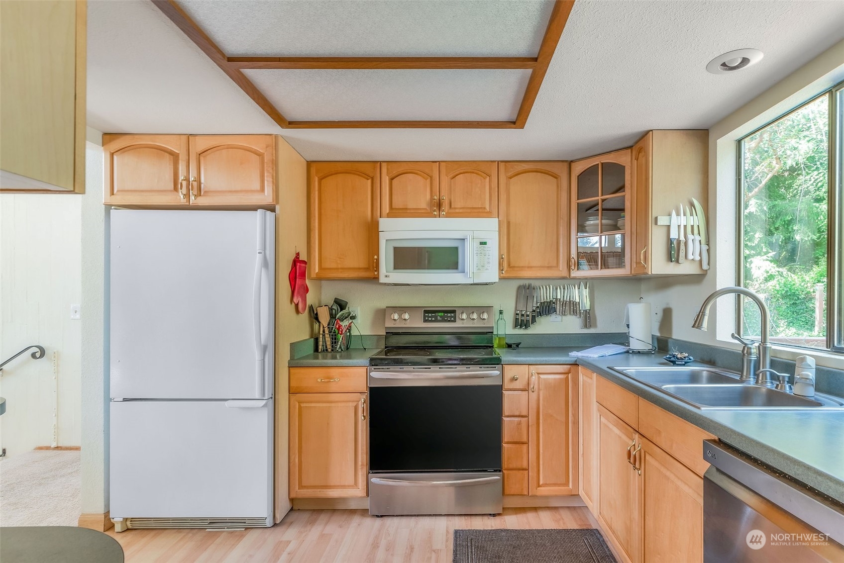26435 Kingsview Loop Northeast Kingston, WA 98346 - Photo 8 of 25 a kitchen with stainless steel appliances granite countertop a refrigerator a sink dishwasher a stove with wooden cabinets and a large window