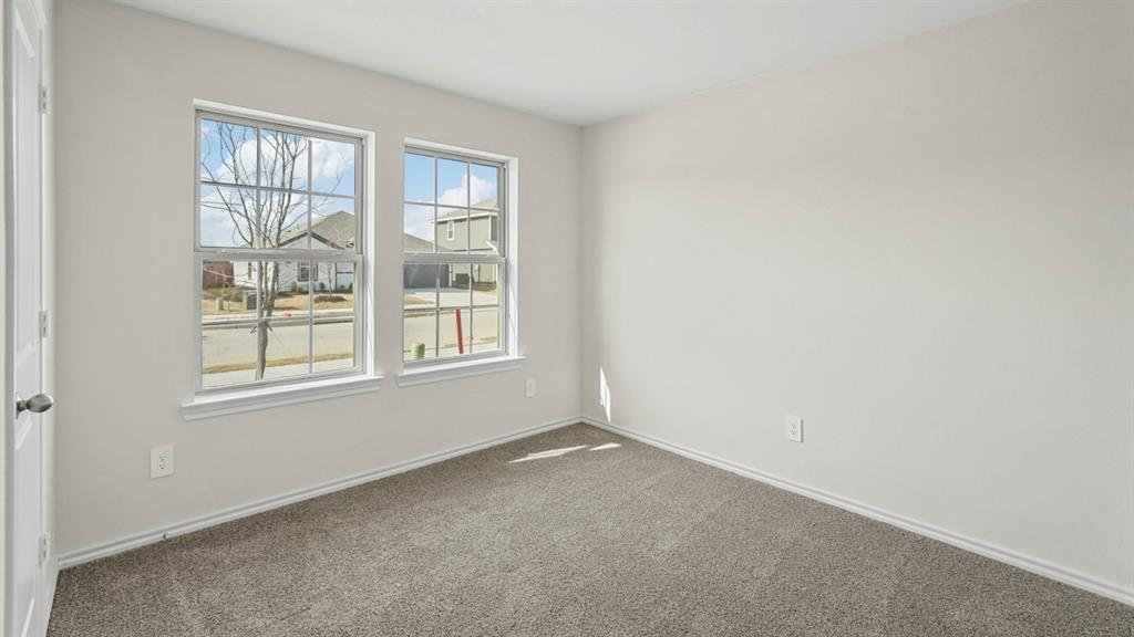 1953 Freeman Street Tyler, TX 75704 - Photo 22 of 32 Bright room featuring two double-hung windows with white trim, light gray wall paint, and gray carpet flooring