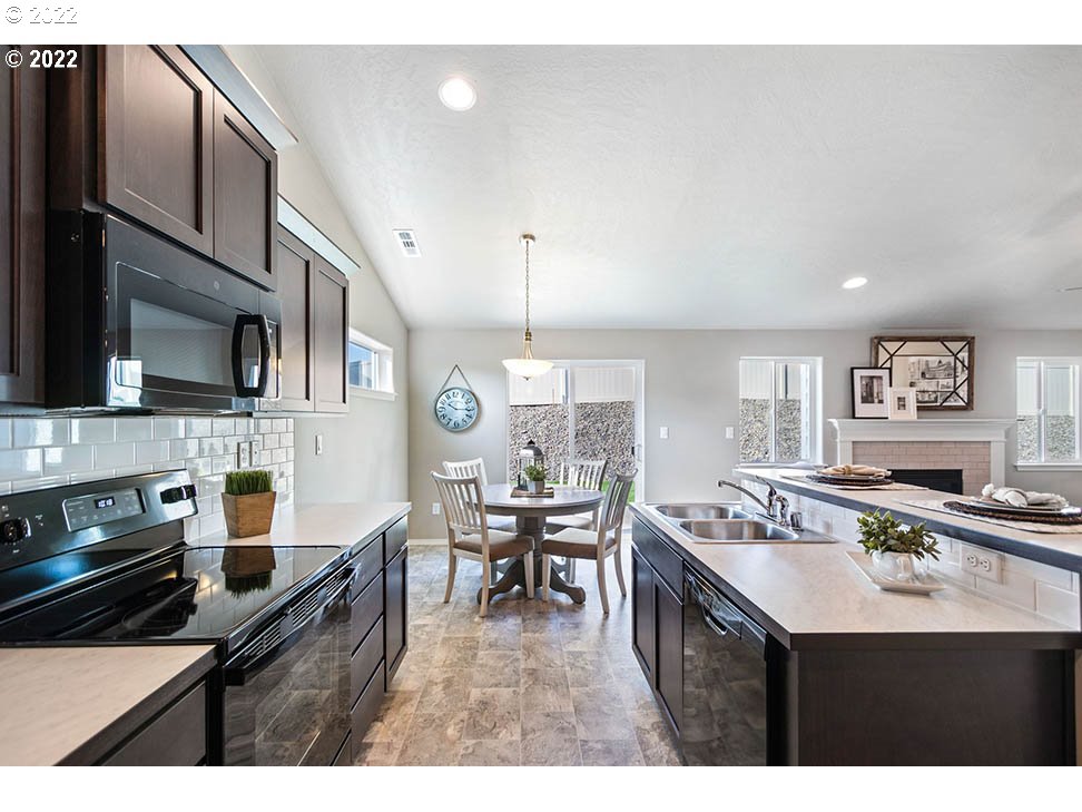 5320 Squirrel Street Springfield, OR 97478 - Photo 3 of 5 a kitchen with stainless steel appliances kitchen island granite countertop a stove a sink a dining table and chairs
