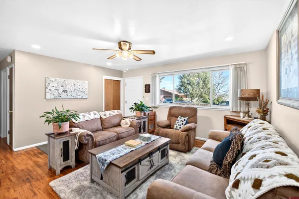 a living room with furniture ceiling fan and a large window