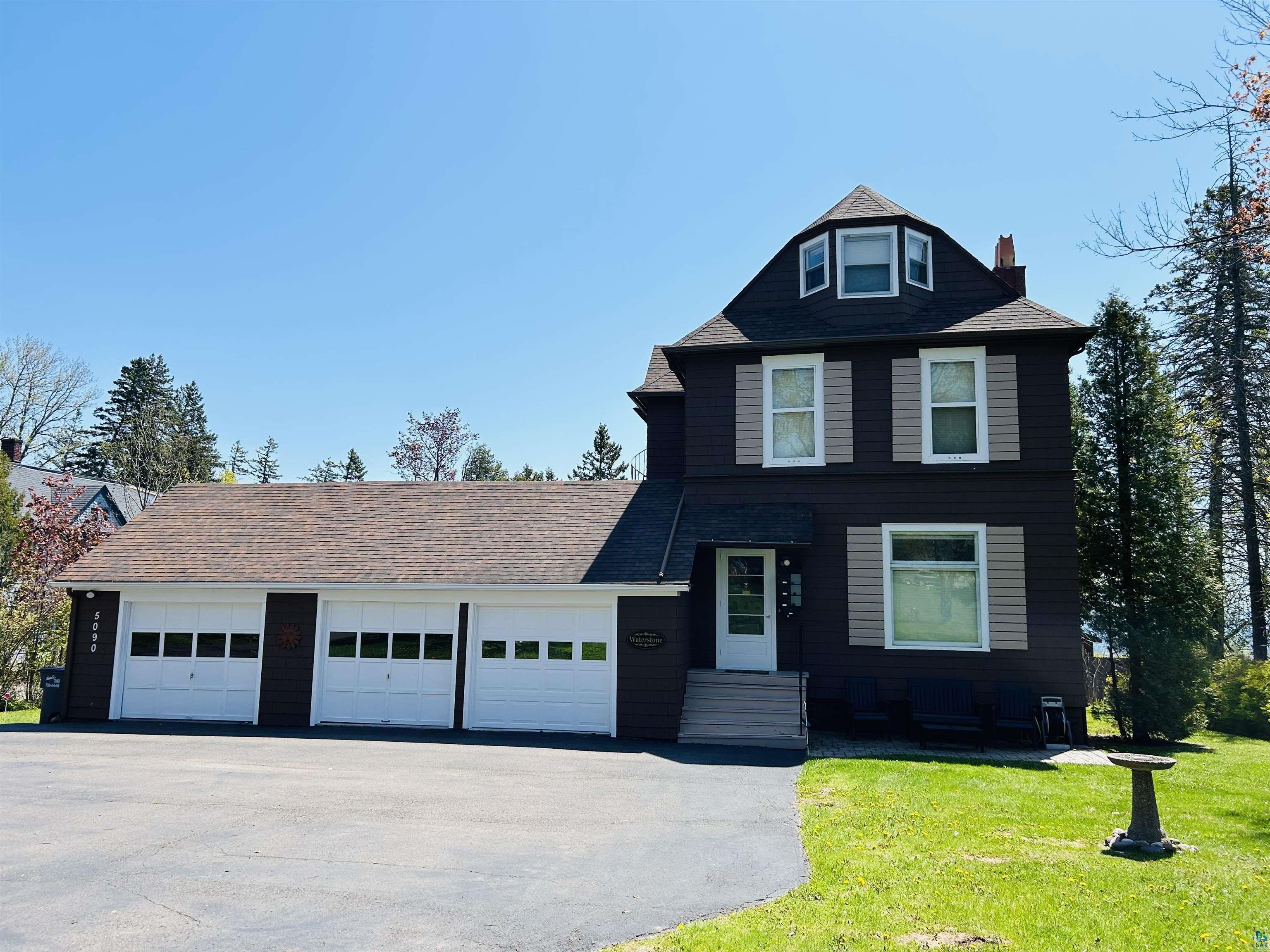 5090 London Road, Unit 1 Duluth, MN 55804 - Photo 1 of 54 Dark-hued exterior featuring multiple white-trimmed windows with shutters, a multi-car attached garage, and a peaked roofline