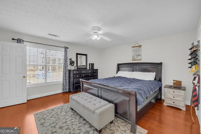 a bedroom with a bed wooden floor and lamp