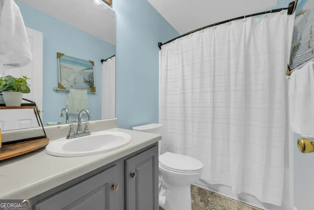 a bathroom with a sink a toilet and shower curtain