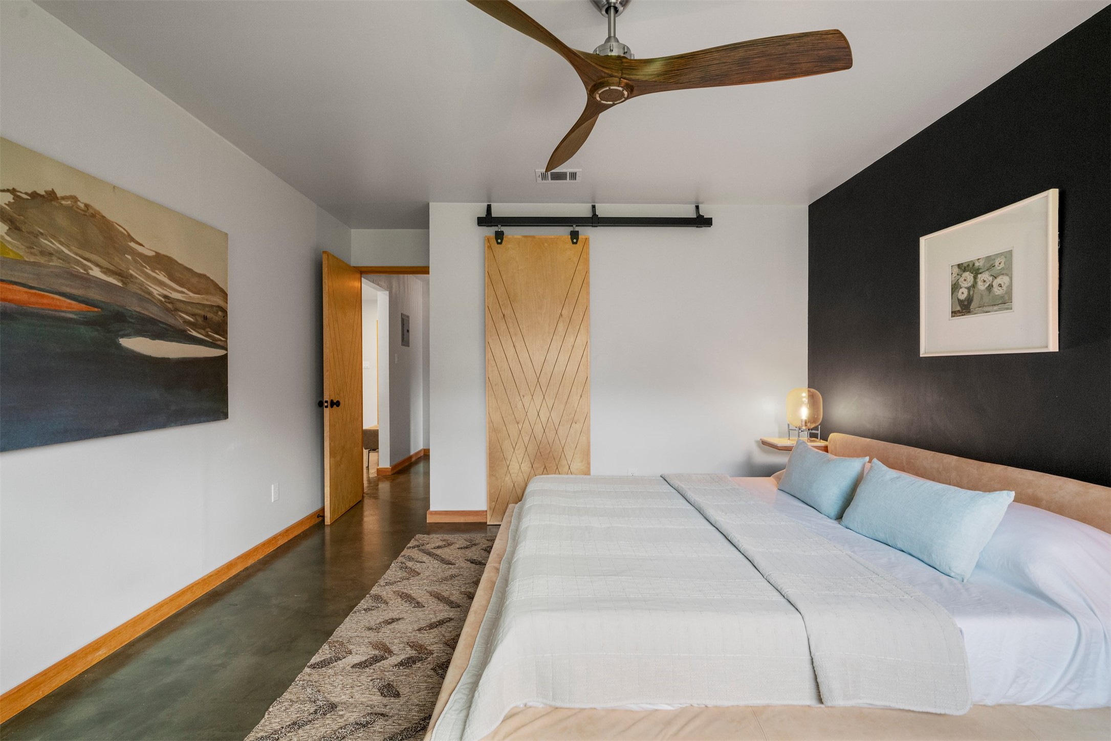 1111 Radam Circle Austin, TX 78745 - Photo 26 of 40 Stained concrete floors continue into the primary bedroom, giving the space a grounded feel that pairs well with the home’s handcrafted interior doors, trim work, and distinctive lighting
