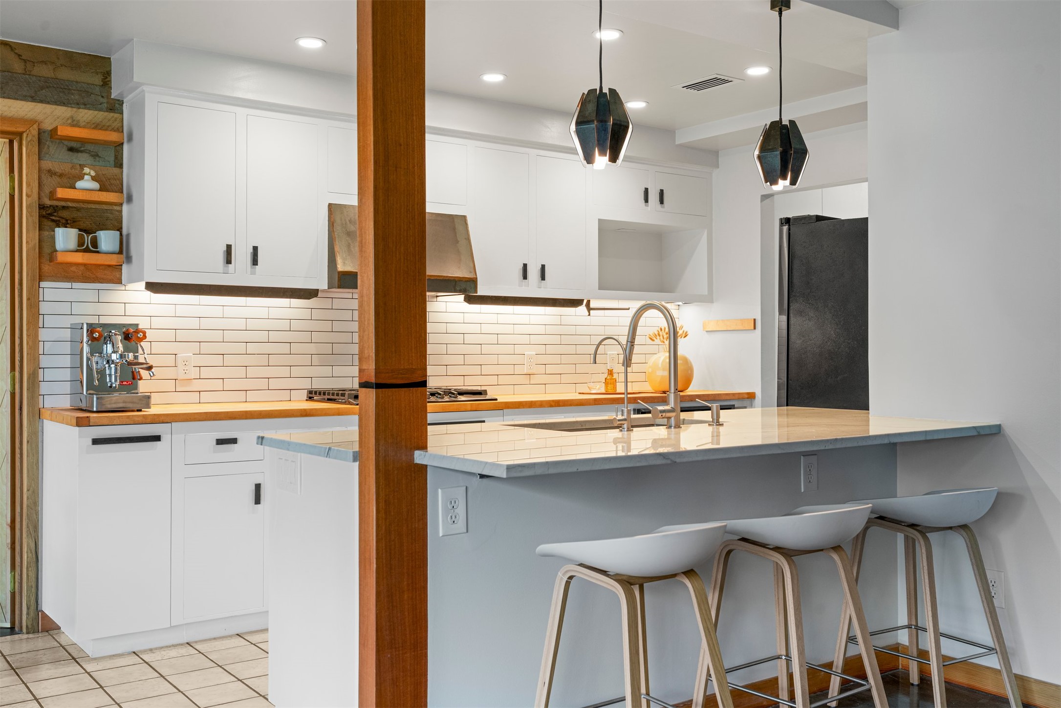1111 Radam Circle Austin, TX 78745 - Photo 3 of 40 The kitchen pairs quartz breakfast seating with butcher block work surfaces, creating a practical layout where prep space and casual seating work side by side