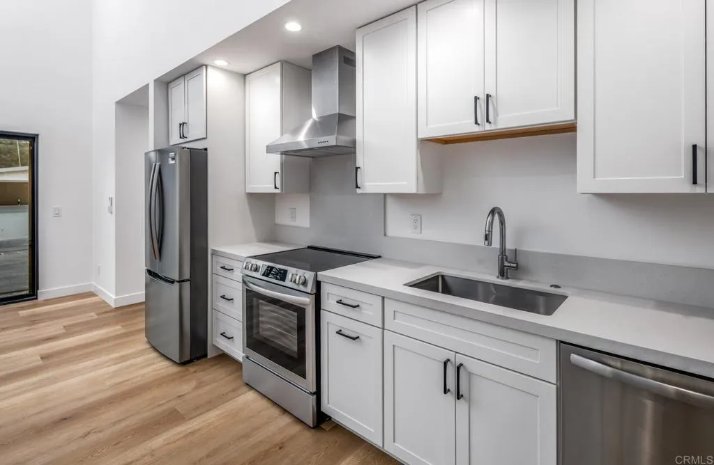 250 Hillcrest Drive Encinitas, CA 92024 - Photo 49 of 54 a kitchen with stainless steel appliances granite countertop a sink a stove a refrigerator and cabinets with wooden floor