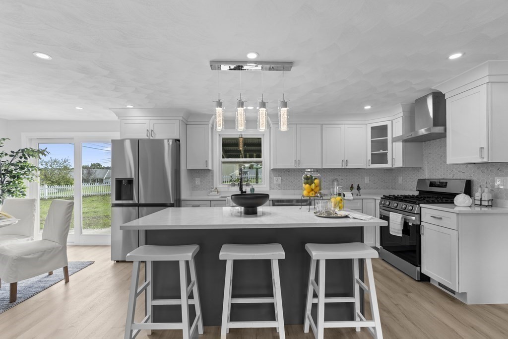 181 Green Street Stoneham, MA 02180 - Photo 5 of 42 a kitchen with stainless steel appliances granite countertop a stove top oven a refrigerator a sink and white cabinets with wooden floor