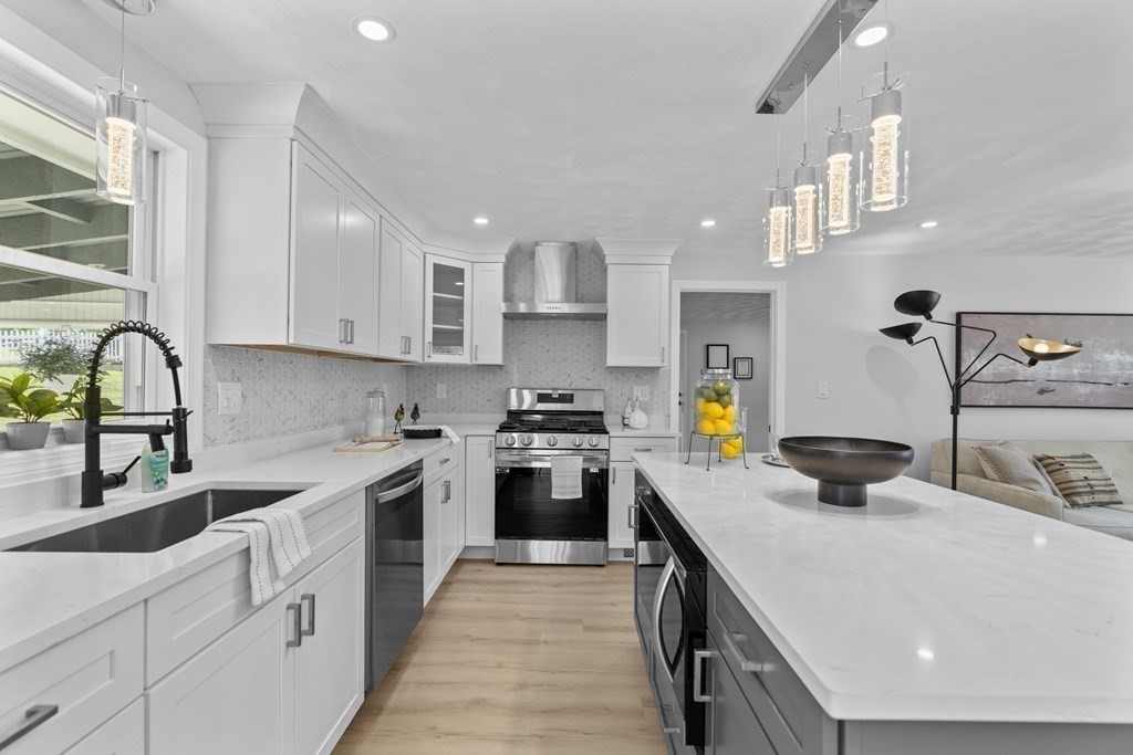 181 Green Street Stoneham, MA 02180 - Photo 8 of 42 a kitchen with stainless steel appliances a stove a sink dishwasher and white cabinets with wooden floor