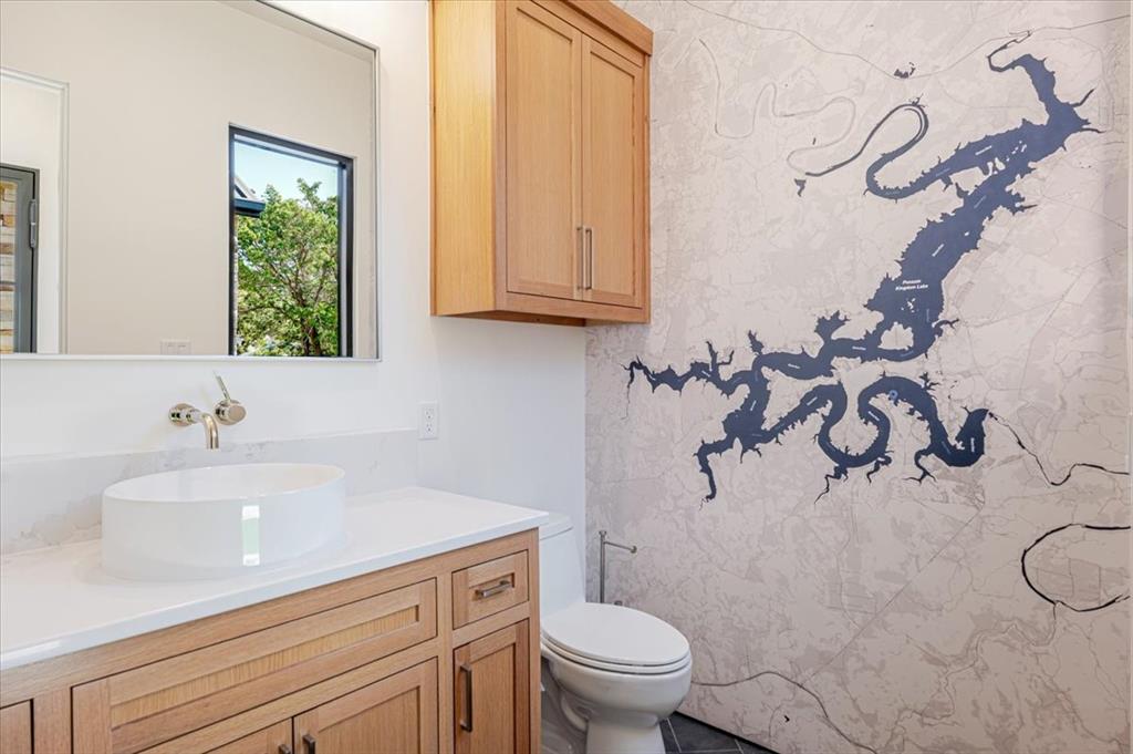 1014 Chaparrel Lane Graford, TX 76449 - Photo 16 of 40 A Playful Nod to Place! Just off the main living area, the powder bath adds a sense of fun and flair with its striking full-wall custom map mural of Possum Kingdom Lake. More than just a visual statement, it’s a bold reminder of where you are—and why you’re here. Warm wood cabinetry, a sleek vessel sink, and polished wall-mounted faucet keep the design crisp and modern, while the window offers a peek outside. Just steps away, a door opens to a gated side yard—secure on both ends—making it an ideal, ready-made dog run or private outdoor nook.