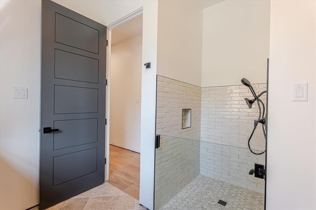 1014 Chaparrel Lane Graford, TX 76449 - Photo 18 of 40 Laundry Room - Part Two - A thoughtful and practical luxury, the dedicated dog wash station, also located in the laundry room, makes life easier for pet owners and outdoor enthusiasts alike. Tucked just inside the laundry, this walk-in tiled stall features a handheld spray wand, easy-clean finishes, and mid-height walls designed for comfort and control during rinses and cleanups. This smart space adds convenience and care to everyday living—without sacrificing the home’s elevated aesthetic.