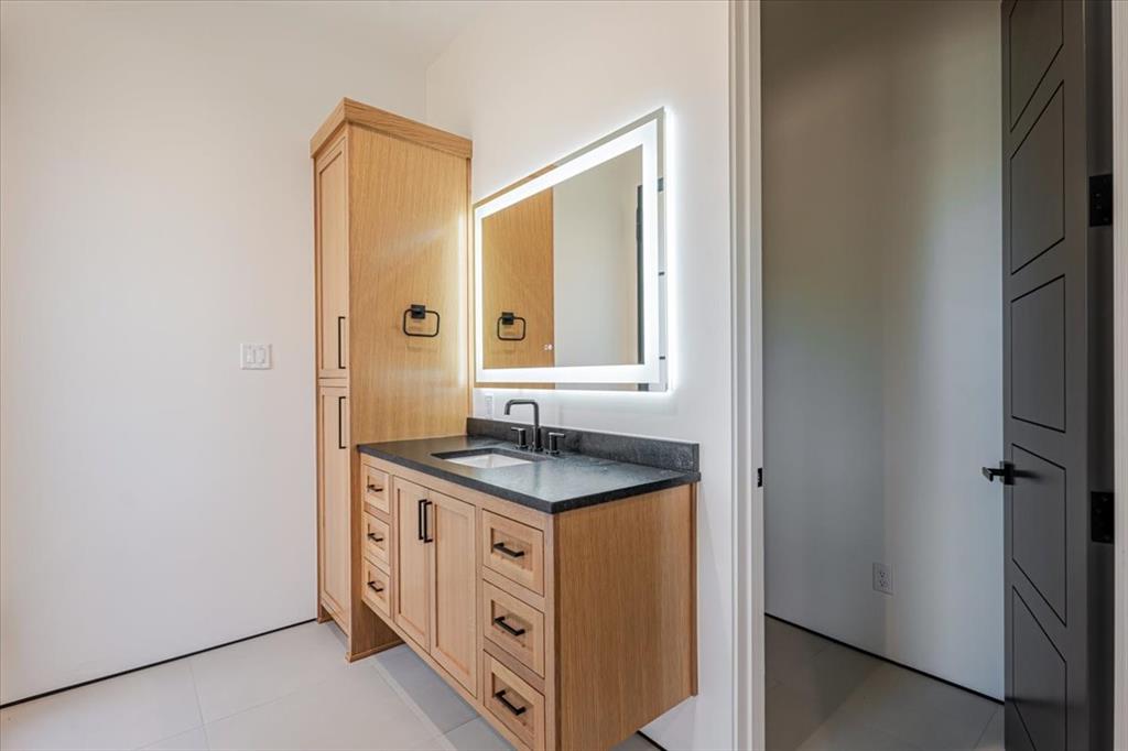 1014 Chaparrel Lane Graford, TX 76449 - Photo 24 of 40 Bath with Pool Access - This well-appointed bath serves both the interior guest wing and the outdoor entertaining areas, with direct access from the side yard for poolside convenience. The sleek vanity with ample storage and LED-lit mirror makes it equally functional for everyday use and accommodating guests coming in from the water.